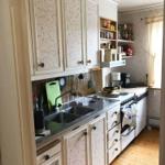 Küche mit weißen Schränken, Edelstahlspüle und Holzboden.