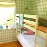 Zimmer mit Doppelstockbett, grün-weißem Tapetenmuster und Holzboden.