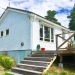 Wohnhaus mit Holzterrasse und Stufen. Umgeben von Bäumen und Grün.