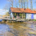 Haus am Wasser mit Terrasse und rotem Dach