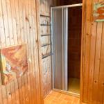 Duschkabine mit Glaswand, Holzwand und zwei Wandbildern.