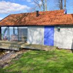 Haus mit rotem Dach und blauer Tür am Wasser