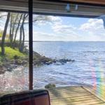 Blick auf See mit Steilufer und Bäumen durch großes Fenster