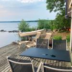 Terrasse mit Tisch und Stühlen am See mit Boot.