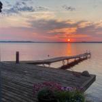 Sonnenuntergang über See mit Holzsteg und Blumenbeet