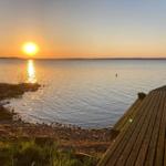 Sonnenuntergang über See mit Holzterrasse und Steilufer