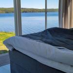 Ein Bett mit Blick auf einen See und Wald.