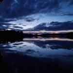 Dämmerung über einem ruhigen See mit Spiegelung des Himmels.