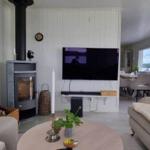 Wohnzimmer mit Kamin, Fernseher und Sofa. Durchgang zur Essnische mit Blick auf Wasser.