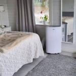 Schlafzimmer mit Bett, Fenster, Spiegel und Sitzgelegenheit.