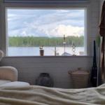 Ein Raum mit Blick auf einen See, ein Sessel und ein Bett sind sichtbar.