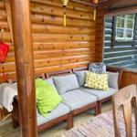 Holzveranda mit Sitzbank, Kissen und Teppich. An der Wand hängt eine rote Laterne.