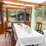 Glasfronten umgeben einen Tisch mit Stühlen und Tischdecke.