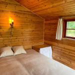 Schlafzimmer mit Holzwand, Bett und Fenster.