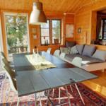 Esszimmer mit Holzwand, Tisch, Stühlen und Sofa. Durchgang zur Terrasse.