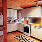 Küche mit weißen Schränken, Holzboden und Fenster zur Außenseite.