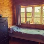 Ein Schlafzimmer mit Holzwand, Bett und Fenster mit Pflanzen.