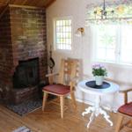 Raum mit Kamin, Tisch und zwei Stühlen vor Fenster.