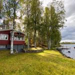 Rotes Haus am See mit Boot und Bäumen