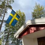 Schwedische Flagge weht vor einem Holzhaus im Wald