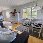 Wohn- und Essbereich mit Kamin, Tisch und Stühlen, Fenster mit Blick auf Wald.