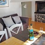 Esstisch mit Flasche und Gläsern vor Sofa und Kamin