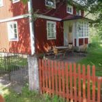 Rotes Holzhaus mit Terrasse und Gartenzaun. Schwedische Flagge an der Tür.