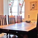 Holztisch mit sechs Stühlen vor Fenster mit Vorhängen