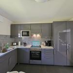 Moderne Küche mit grauen Schränken, Edelstahlgeräten und Arbeitsplatte.