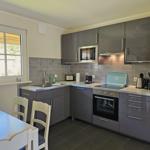 Moderne Küche mit grauen Schränken, Edelstahlgeräten und Fenster zum Garten.