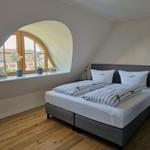 Schlafzimmer mit Dachschräge, großem Fenster und Bett mit Bettwäsche.