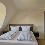 Schlafzimmer mit Doppelbett, zwei Nachttischen und einem Bogenfenster.