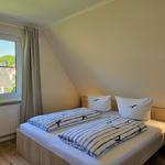 Schlafzimmer mit Doppelbett, Fenster und Schreibtisch