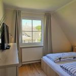 Schlafzimmer mit Doppelbett, Fenster und Schreibtisch.