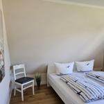 Schlafzimmer mit Doppelbett, Stuhl und Wandbild.