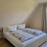 Schlafzimmer mit Doppelbett, Fenster und Holzboden.