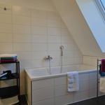 Badezimmer mit Badewanne, Dusche und Dachfenster. Handtuchhalter und -ständer.