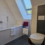 Badezimmer mit Badewanne, Dusche und Toilette unter Dachschrägen mit Dachfenster.