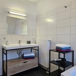 Badezimmer mit Waschbecken, Spiegel, Duschwanne und Handtüchern.