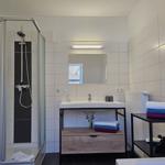 Badezimmer mit Dusche, Waschbecken und Handtuchständer.