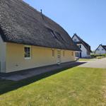 Haus mit Strohdach, Garten und gepflastertem Weg.