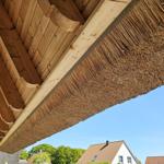 Dach mit Stroh und Holzkonstruktion unter blauem Himmel