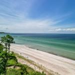 Strand mit Sand, Meer und Brücke unter blauem Himmel