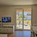 Wohnzimmer mit TV, Esstisch und Blick auf die Terrasse.