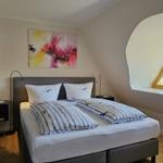 Schlafzimmer mit Doppelbett, Wandbild und Bogenfenster.