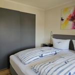 Schlafzimmer mit Doppelbett, Kleiderschrank und Wandbild.