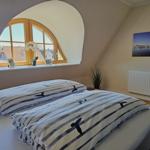 Schlafzimmer mit Bett, Fenster und Wandbild