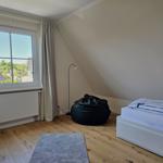 Schlafzimmer mit Dachschräge, Bett, Sitzsack und Fenster mit Blick.