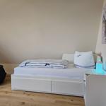 Schlafzimmer mit weißem Bett, Holzboden und Wandbildern