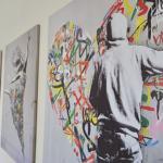 Wand mit drei modernen Kunstwerken, eins mit Graffiti-Elementen.